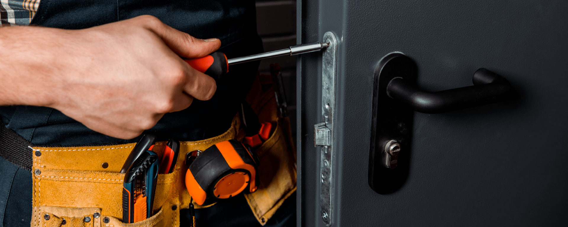 Certified Installer CDVI | A closeup of an engineer's hands and the side of a door as they use a screwdriver to screw a lock faceplate into position